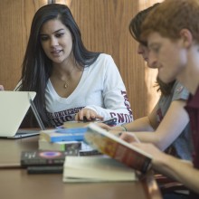 Three students sit studying at a table.