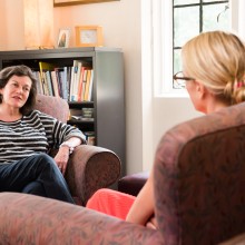 A female student seated in a red chair speaks with a female counselor.